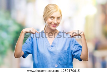 Young beautiful blonde doctor surgeon nurse woman over isolated background looking confident with smile on face, pointing oneself with fingers proud and happy.