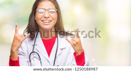 Young arab doctor woman over isolated background shouting with crazy expression doing rock symbol with hands up. Music star. Heavy concept.