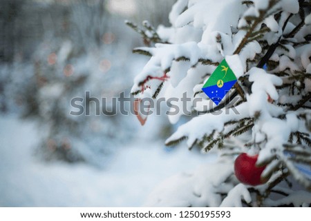 Christmas Island flag. Christmas background outdoor. Xmas tree covered with snow and decorations and a national flag. Christmas and New Year holiday greeting card.