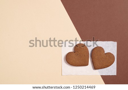 Two ginger cookies in shape of heart on colored background, top view with space for text