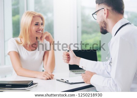 Male doctor is talking to female patient in hospital office. Healthcare and medical service.