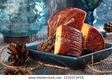 Home-made cheese cut into pieces, on a blue wooden background. Fir cones and a glass of wine. The concept of a home cheese factory.