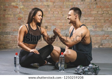 Fitness man and woman giving each other a high five after the training session in gym. Fit couple high five after workout in health club. Royalty-Free Stock Photo #1250259208