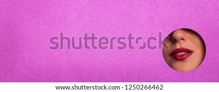 View of bright lips through hole in shimmer viloet paper background. Make up artist, beauty concept. Ready to new year party. Cosmetics sale. Beauty salon advertising banner with copy space.