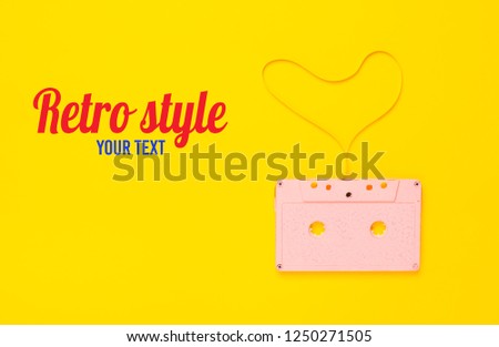 Heart shape from audio cassette tape over yellow paper background, top view. Hipster Love.