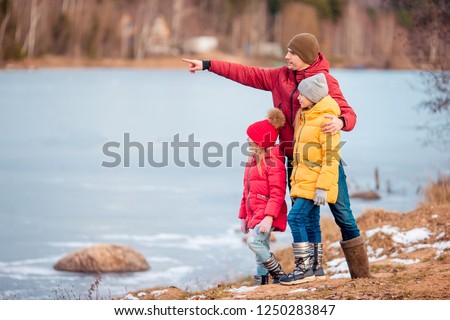 Family of father and kids enjoying beautiful landscape near frozen lake. Winter day.