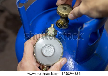Regulator for propane-butane gas cylinder and accessories on a wooden workshop table. Gas accessories in the workshop. Dark background. Royalty-Free Stock Photo #1250294881