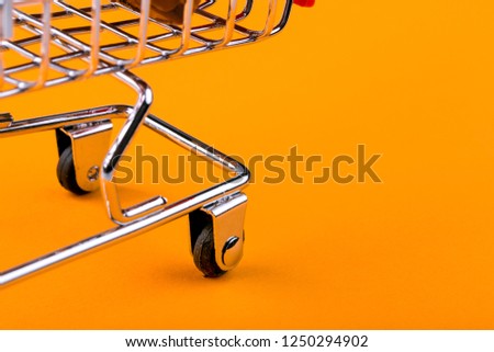 shopping trolley on orange background, shopaholic concept