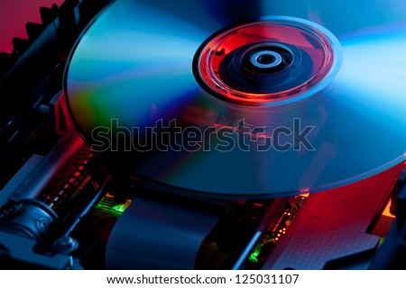 The laser disk lies in the open disk drive. Parts of electronic schemes are visible Royalty-Free Stock Photo #125031107