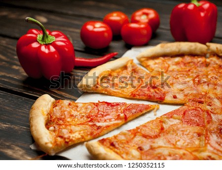 pizza on a wooden table with ingredients, tomato, pepper, sunflower oil