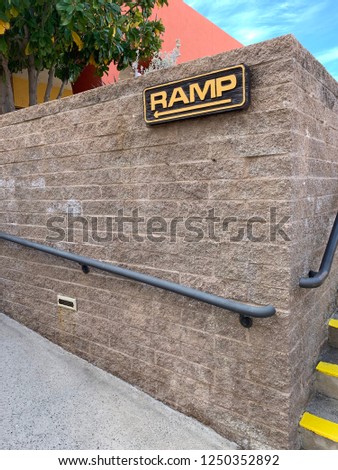 Ramp sign near steps on side of outdoor wall
