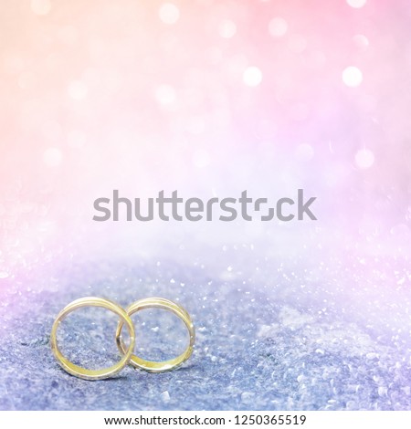 Soft pink wedding background. Beautiful flyer, billboard or web banner With copy space. Two wedding Gold Rings standing on the bezel on delicate light background. Square image