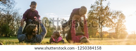 Wide view image  of happy young family of five having fun in an autumn park.