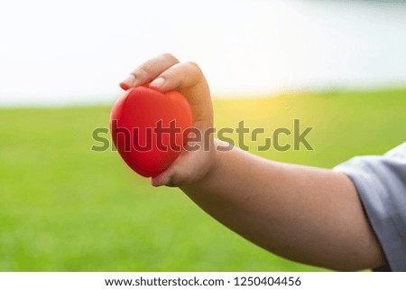 Hand hold red cartoon balloon heart and show to tell save heart and health.green background