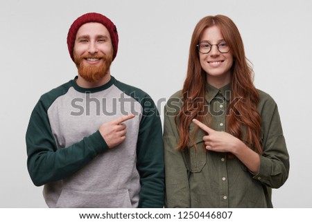 Happy european couple feels happy in their relationship, smiles and indicates with four finger each other, isolated over white background. Portrait of young straight family