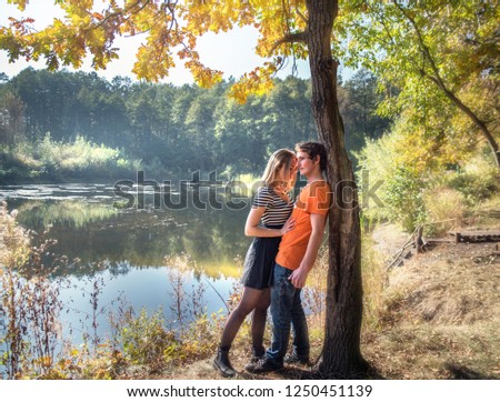 A boy and a girl in love on the shore of a forest lake amid the haze of air.