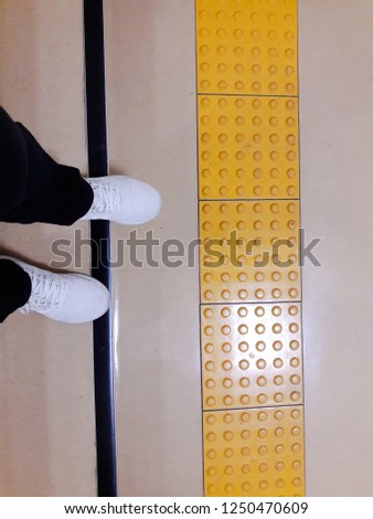 his Feet Standing in Front of the Sidewalk with Tactile Tiles to Navigate Blind People. Yellow Tactile Paving Slabs.