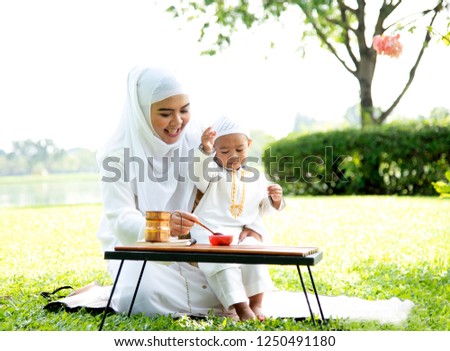 Muslim mother happy with her son eating jelly in the park.