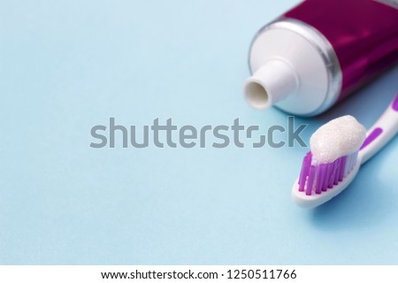 toothbrush with toothpaste and tube on a blue background, close-up, teeth care concept, copy space