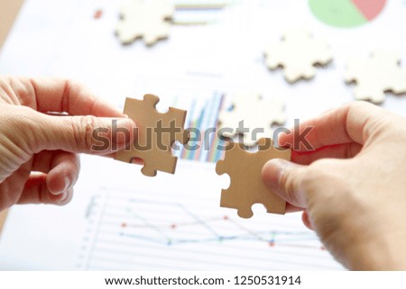 Close-up of hands show jigsaws over chart of business. business concept Royalty-Free Stock Photo #1250531914