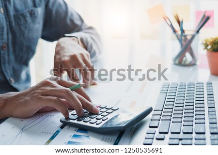 Close up of businessman or accountant hand holding pen working on calculator to calculate business data, accountancy document and laptop computer at office, business concept
 Royalty-Free Stock Photo #1250535691