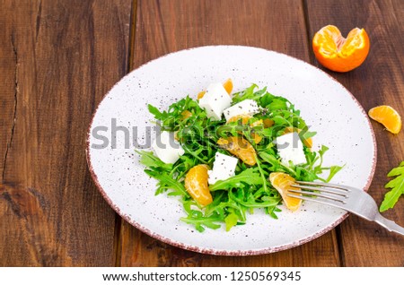 Delicious fruit and vegetables salad. Tangerine, feta cheese, arugula and chia seeds in plate. Healthy food concept. Studio Photo