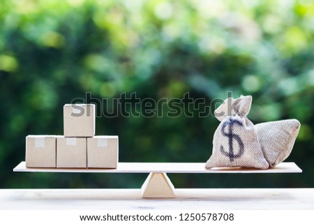Money and supply concept : Money dollar bag and supply products on balance scale on wooden table depicts balancing between risk and return. Investment between money and supply reverse. Royalty-Free Stock Photo #1250578708