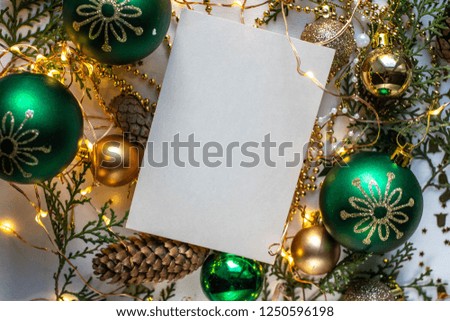 card mockup with green and golden frame for Christmas. fir, stars, cones and tree balls on white table