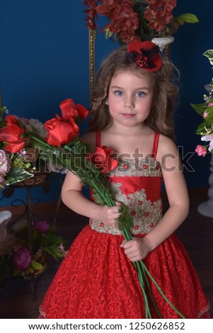 portrait of a little princess girl in a red dress with flowers in her hands and around her