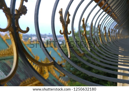 Curved steel fence window on pavement in temple to Shwedagon pagoda in Yangon, Myanmar
