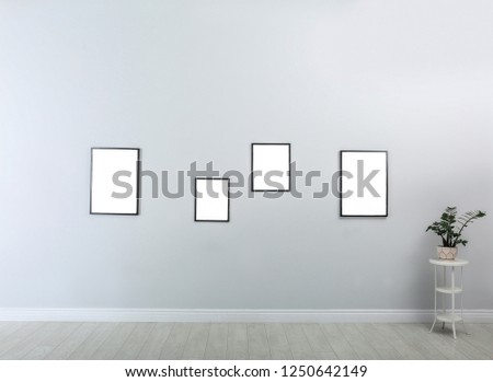 Frames with empty canvases on wall in modern art gallery. Mockup for design