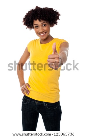 Cute looking female showing thumbs up sign to the camera, curly haired.