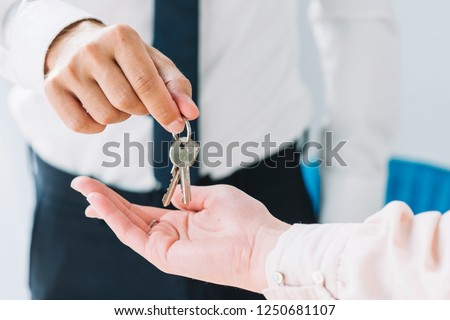 Agents are giving house keys of customer and holding dollar us bank at agency office. Agreement concept.
