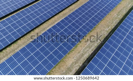 Aerial low altitude bird view picture of photovoltaic station also known as a solar park is large-scale PV system designed for supply of merchant power into the electricity grid by sunlight energy
