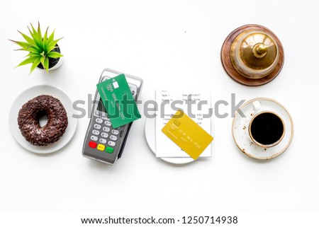 Payment terminal on restaurant desk near bill, service bell, coffee on white background top view
