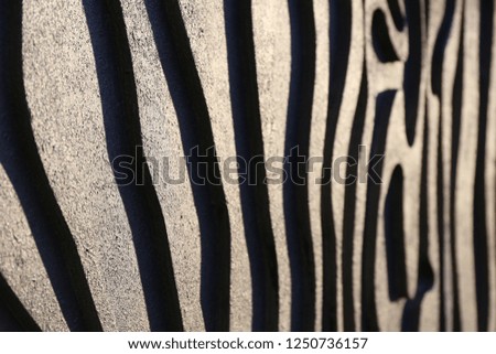 Close up view of a striped surface with white and dark shapes lighted by the sun. Abstract design of a modern wall with many curving lines. Bright textured wall.