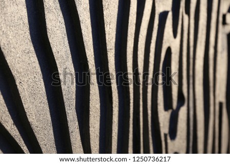 Close up view of a striped surface with white and dark shapes lighted by the sun. Abstract design of a modern wall with many curving lines. Bright textured wall.