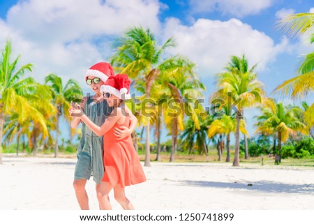 Adorable kids in Santa hats during beach Christmas vacation having fun together