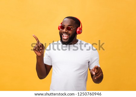 Young African American man wearing headphone and enjoy music over yellow gold Background
