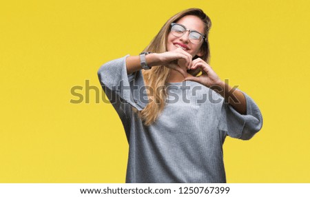 Young beautiful blonde woman wearing glasses over isolated background smiling in love showing heart symbol and shape with hands. Romantic concept.