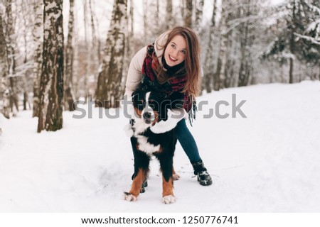 girl playing with dog in winter forest