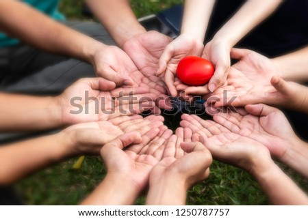 One hand hold red cartoon balloon heart put on many hands touch in circle shape,show to tell save heart and health.green background,healthy concept