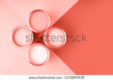 Banner with color of the year 2019 - Living Coral. Four open cans of paint on bright symmetry background. Place for text. Renovation concept.