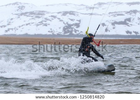 Professional kite boarding rider sportsman with kite rides blue lagoon enjoying fun joy happy leisure rest relaxing time. Recreational activity, extreme active air water sports on sea at winter snow.