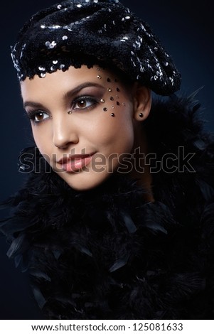Portrait of beauty smiling in black sequin party hat and boa, with glamorous makeup of rhinestones.