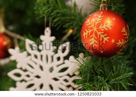 Christmas Trees & Decorations. Red bauble and white snowflake hanging from Christmas tree.