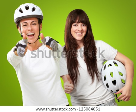 Two Cyclist Woman Showing Thumb Up Sign On Green Background