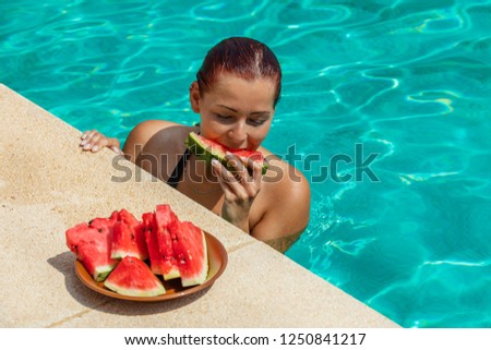 Young woman with red hair enjoying watermelon at the pool