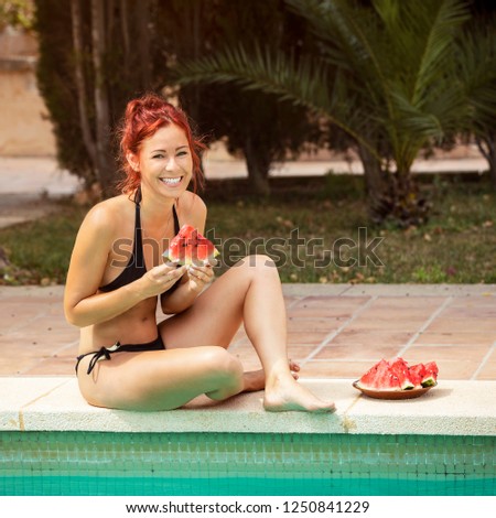 Young woman with red hair enjoying watermelon at the pool