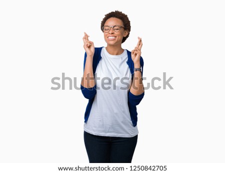 Young beautiful african american woman wearing glasses over isolated background smiling crossing fingers with hope and eyes closed. Luck and superstitious concept.